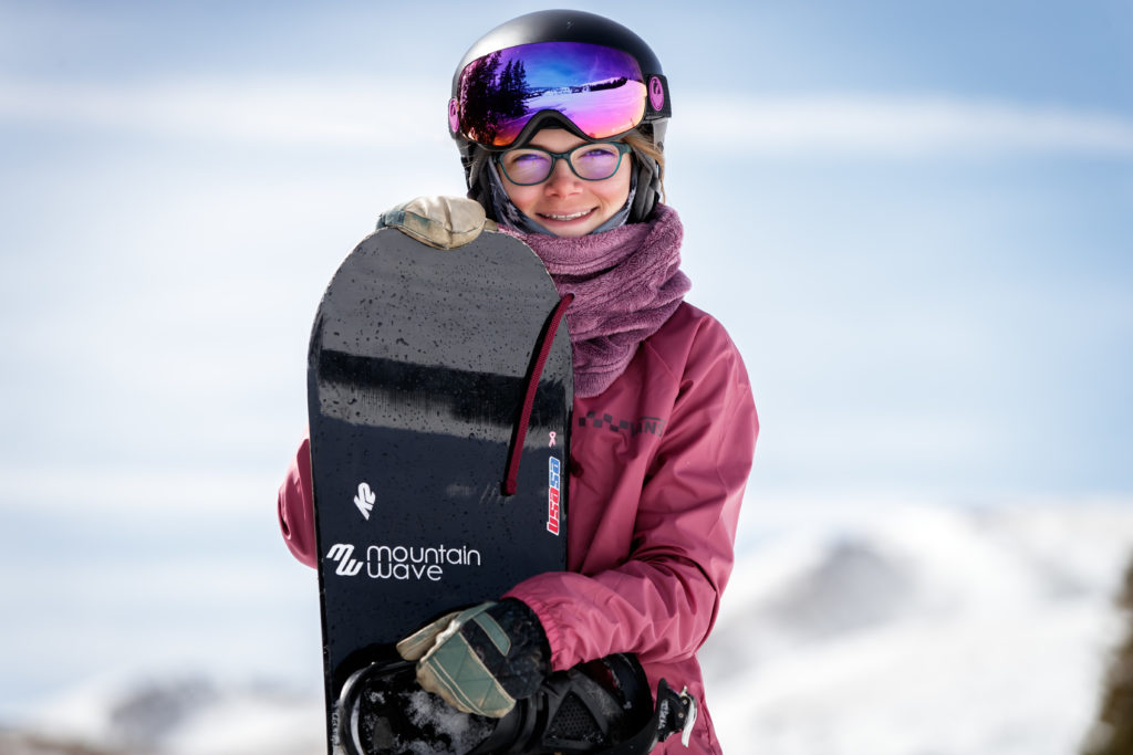 A person wearing a helmet posing on a snow covered slope

Description automatically generated